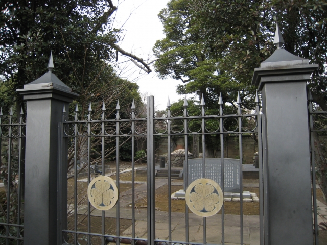 Historic Japanese graveyard in Nishi Nippori, Tokyo, behind an ornate iron gate.