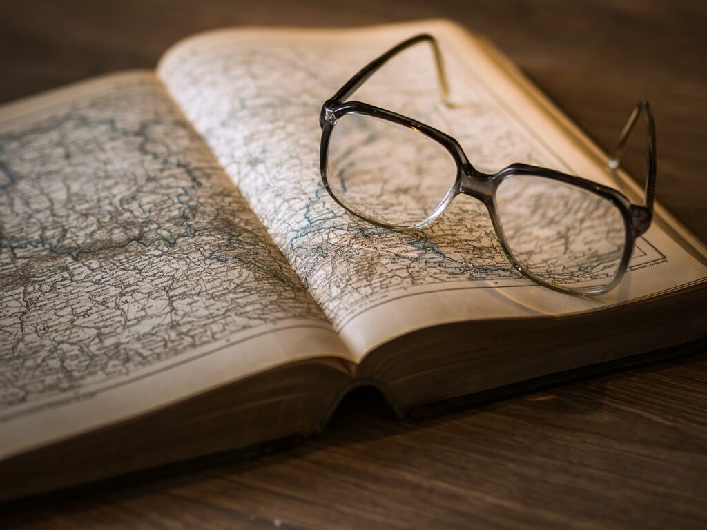  A pair of glasses resting on an ancient map, symbolizing exploration and discovery of knowledge.