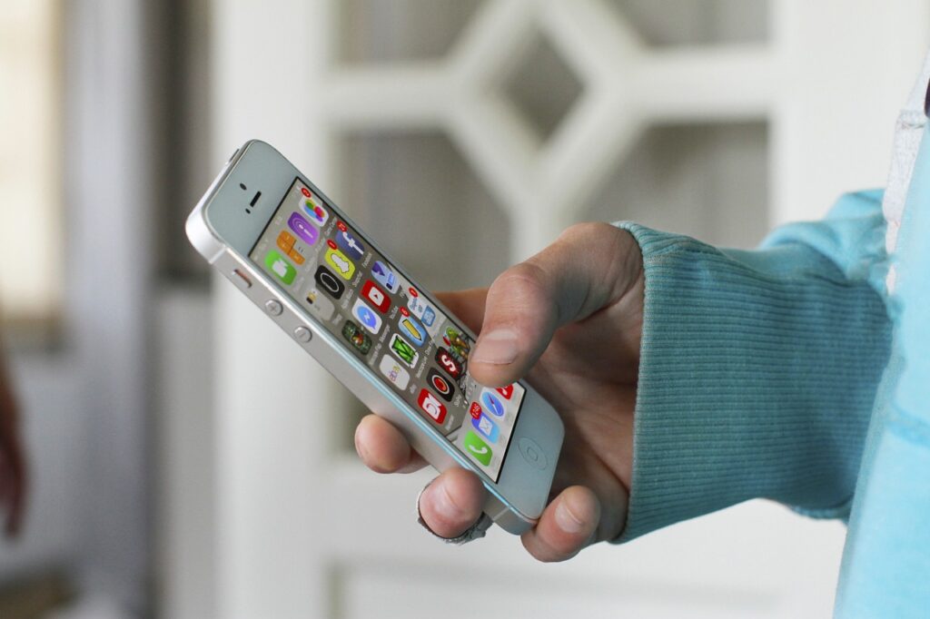 A person holding a smartphone, navigating through apps.