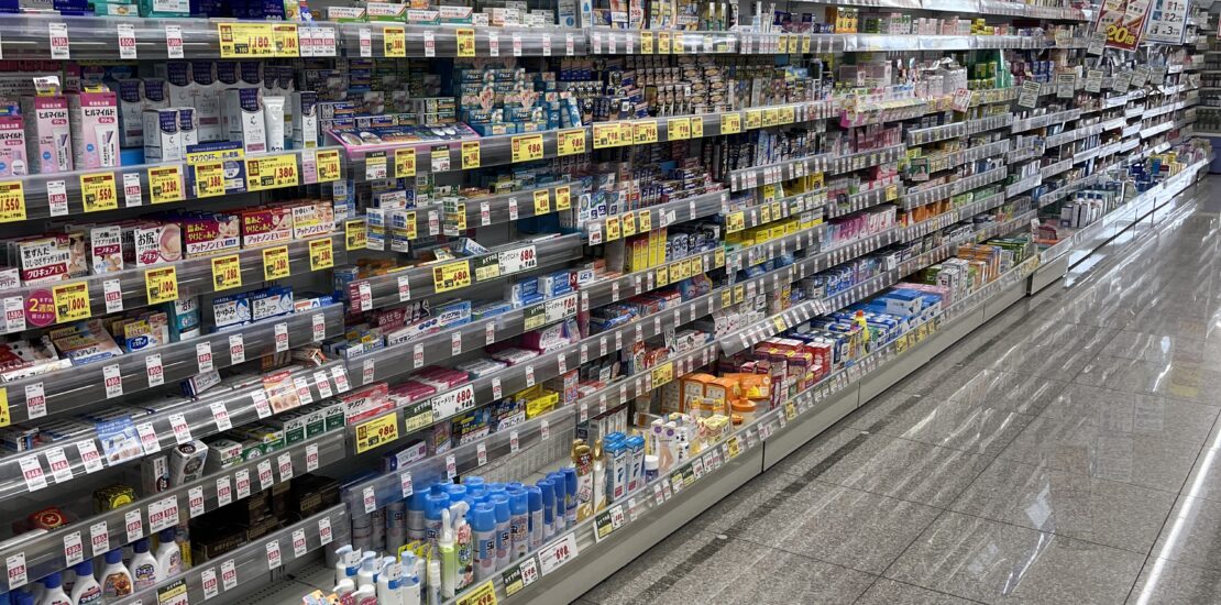 Japanese supermarket aisle with a variety of health and hygiene products, including ointments, skincare, and personal care items.