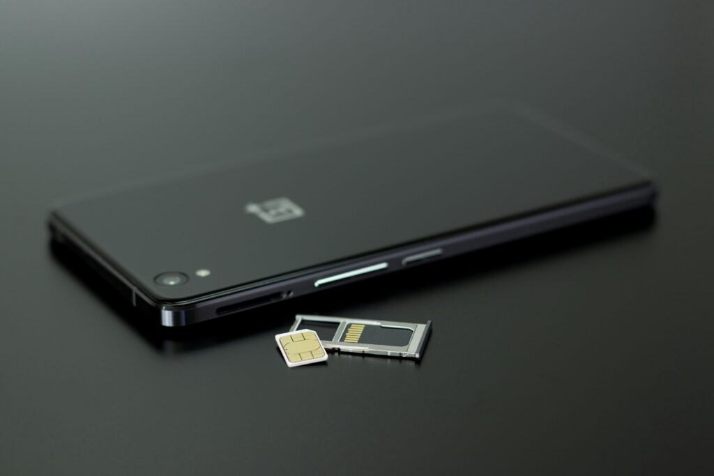 Smartphone with a SIM card and SIM card tray on a black surface.