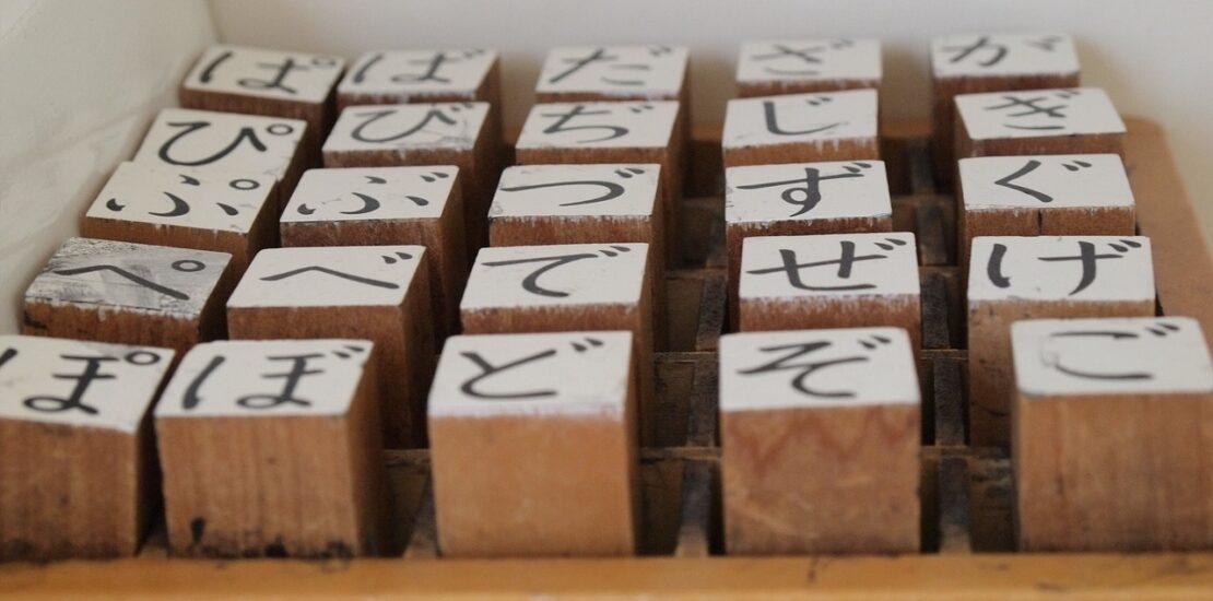 Wooden stamps with hiragana characters neatly arranged in a box.