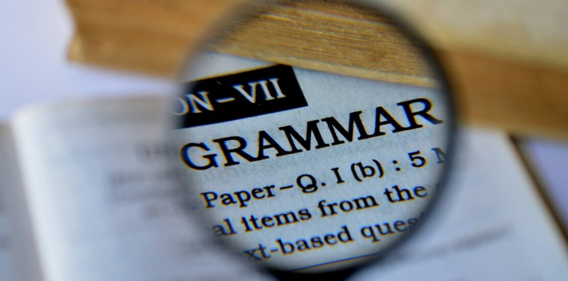 A magnifying glass highlighting the word 'Grammar' in a dictionary, focusing on Japanese grammar study.