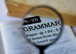 A magnifying glass highlighting the word 'Grammar' in a dictionary, focusing on Japanese grammar study.