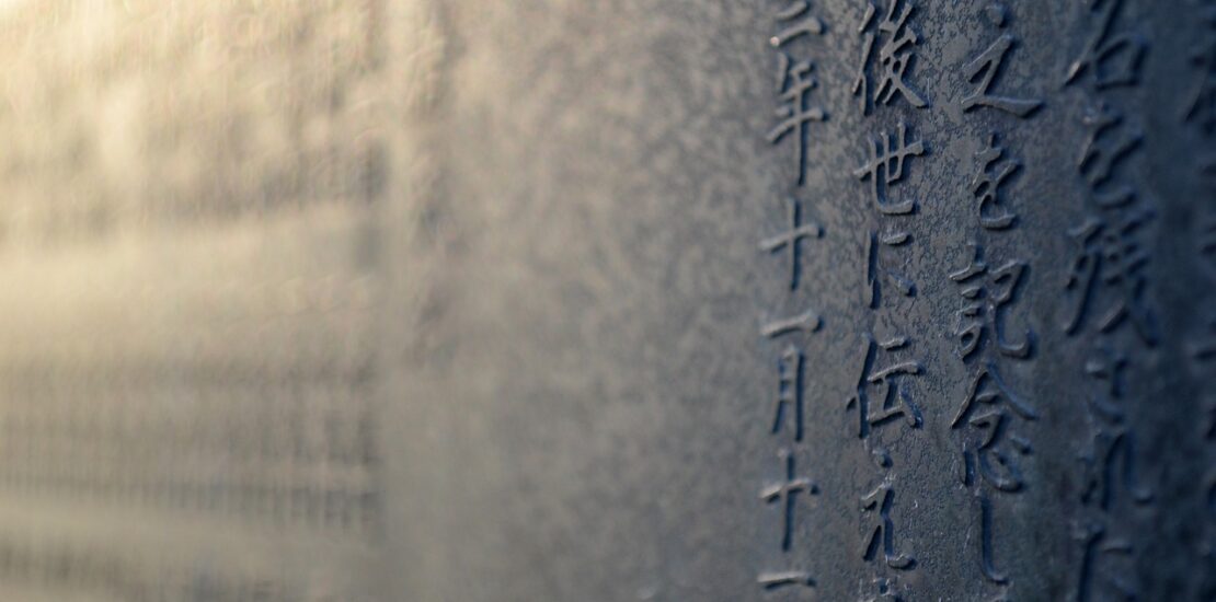 Close-up of Japanese kanji characters engraved on a stone surface, slightly blurred in the background.