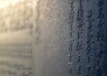 Close-up of Japanese kanji characters engraved on a stone surface, slightly blurred in the background.