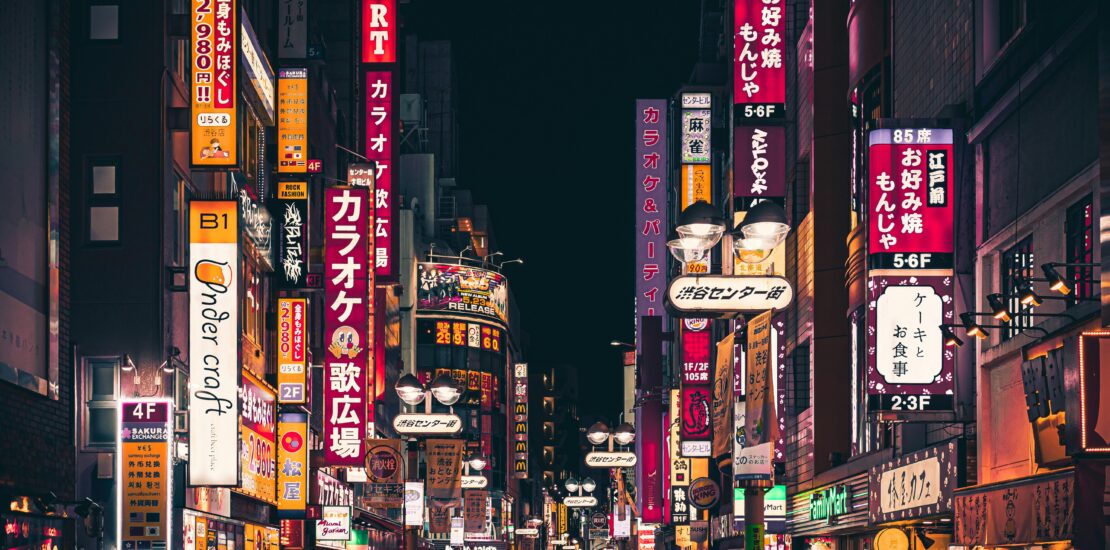 Neon-lit street in Nishi Nippori, Tokyo, bustling with activity at night.