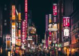 Neon-lit street in Nishi Nippori, Tokyo, bustling with activity at night.