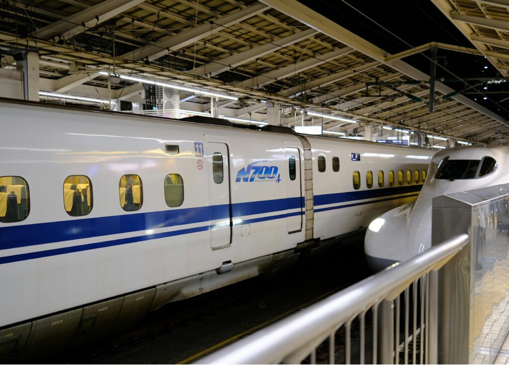 A sleek white bullet train speeding through a dimly lit underground station.