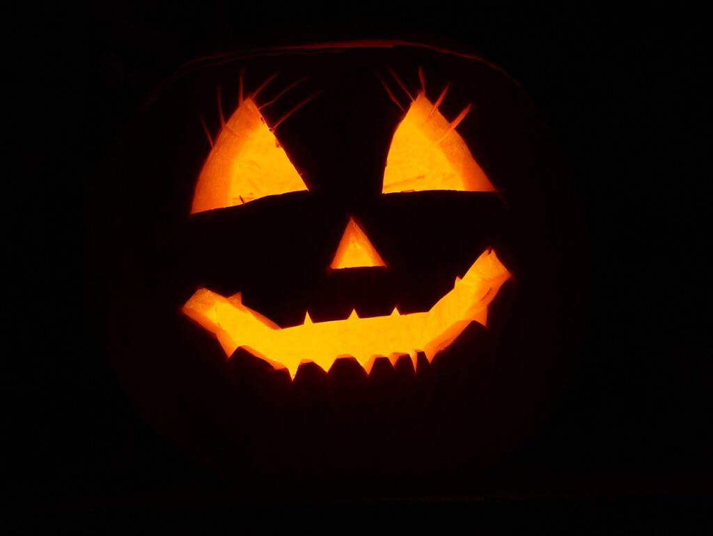 A glowing Jack-o'-lantern carved with a mischievous grin, lit up against the dark night in Halloween Osaka.