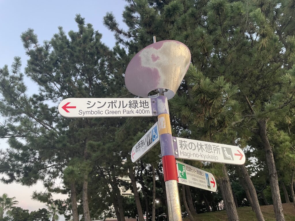 A park direction sign pointing to Symbolic Green Park and nearby rest areas. Title: Direction to Symbolic Green Park at Rinku Town