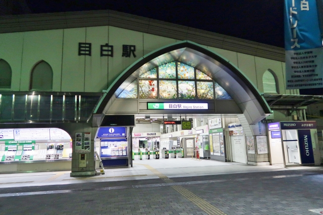 The entrance of Mejiro Station at night, illuminated by soft lighting.