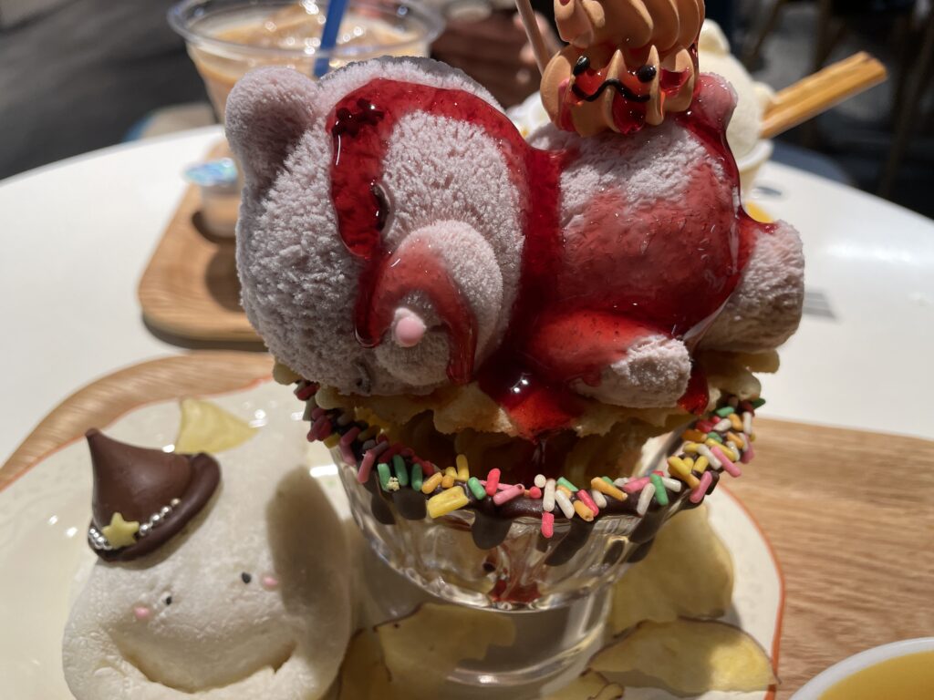 A Halloween dessert with a teddy bear-shaped treat covered in strawberry sauce, paired with a cute ghost-shaped mochi.