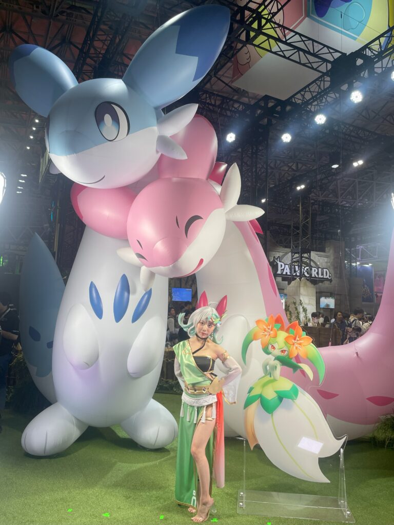 Cosplayer posing beside giant Palworld character inflatables at TGS 2024.