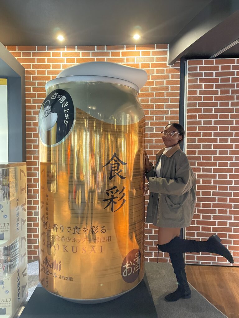 A visitor posing next to a giant golden can of Asahi inside the museum.