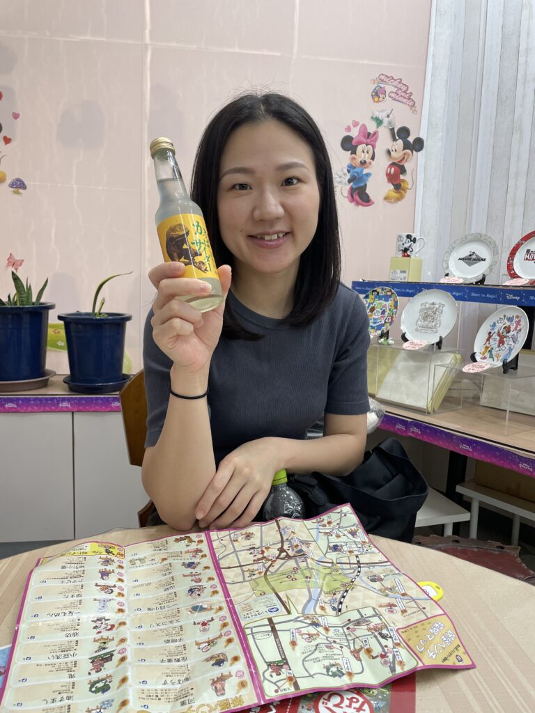 A woman holding a bottle of Kappa cider and looking at a map of Fukusaki City.