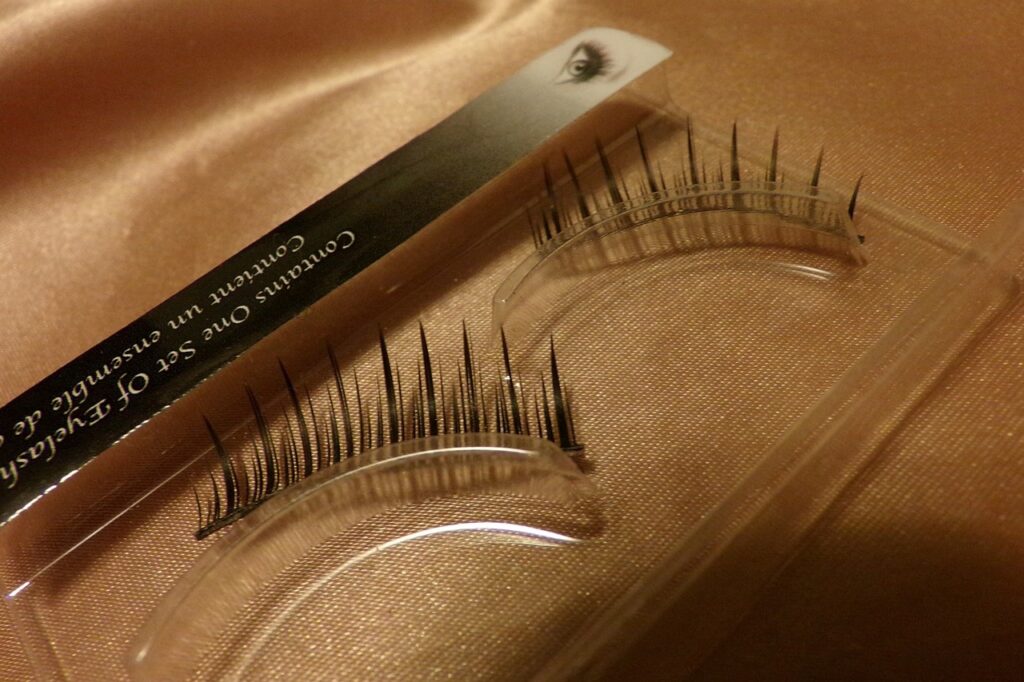 A pair of artificial eyelashes on a soft, satin surface, ready for application.