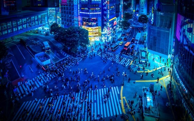 Shibuya Scramble Crossing at night illuminated by neon lights and bustling crowds.