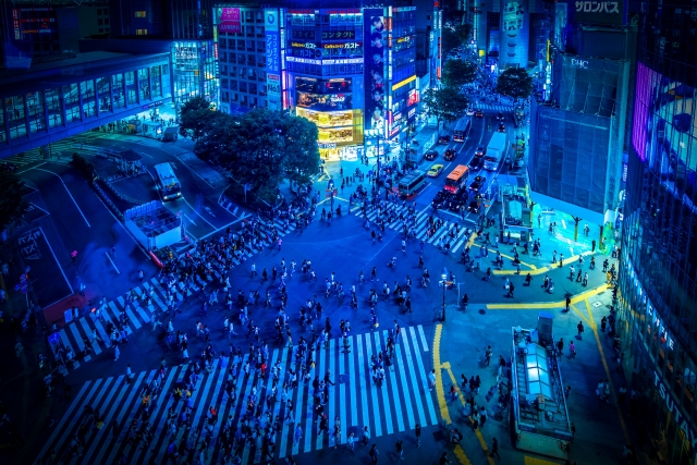 Shibuya Scramble Crossing at night illuminated by neon lights and bustling crowds.