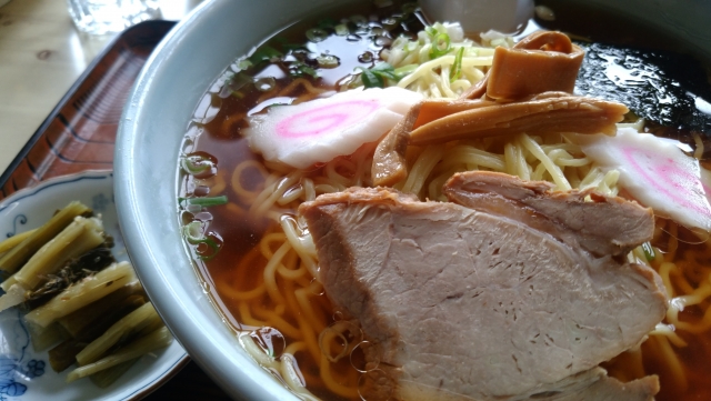  A bowl of shoyu ramen with slices of roast pork, bamboo shoots, and pink-spiraled naruto fish cakes.