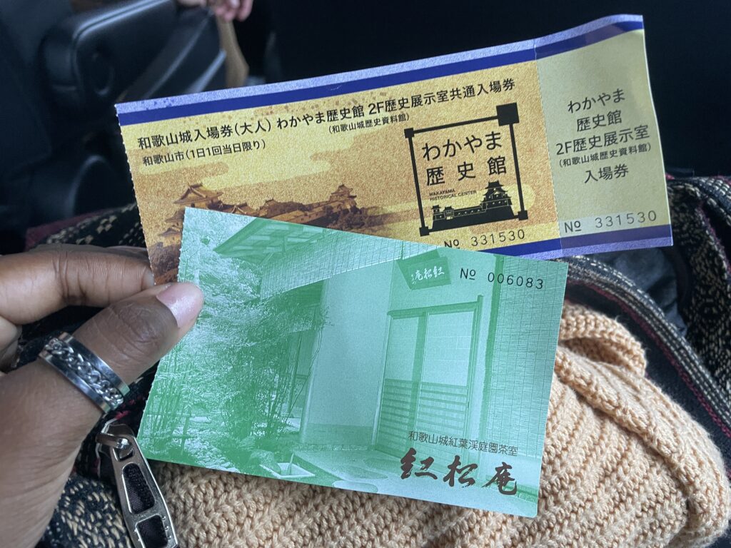 Close-up of Wakayama Castle and Koshoan tea house admission tickets held in hand, ready for a day of exploring.