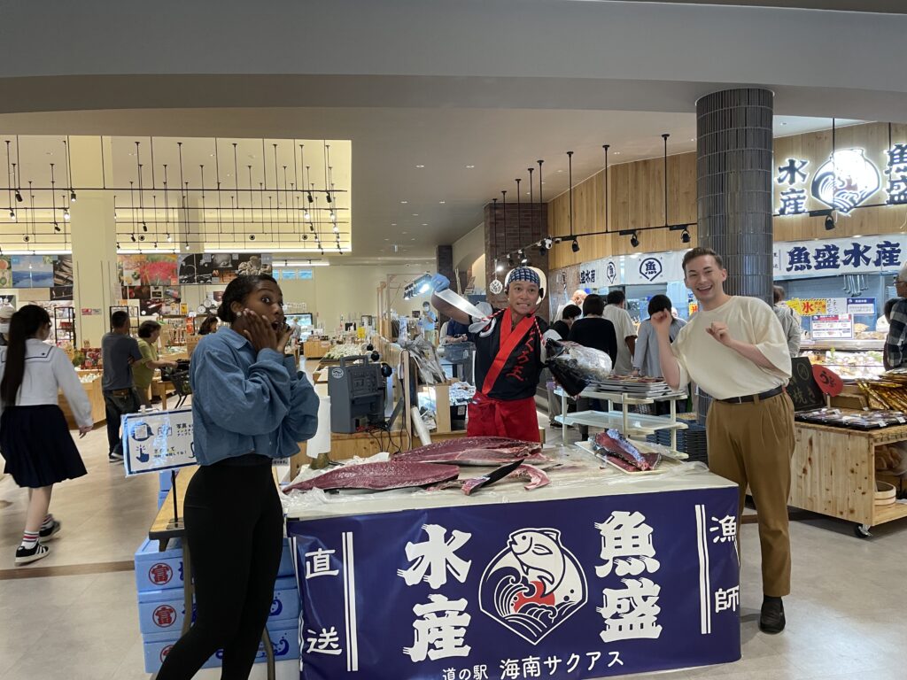 Visitors react with excitement as a professional prepares to cut a large tuna during a live demonstration at Sakuasu Roadside Station.