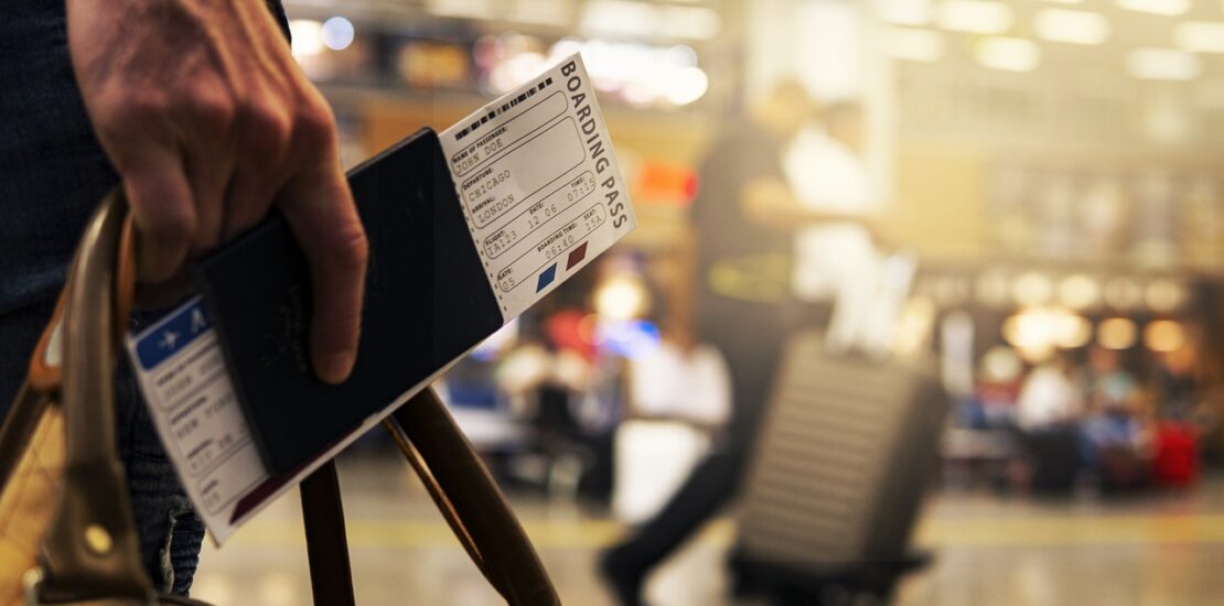 A close-up of a traveler holding a passport and boarding pass at the airport.