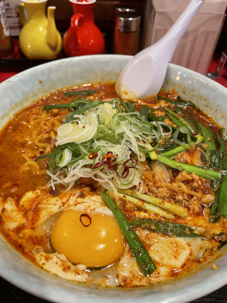 A bowl of shoyu ramen garnished with soft-boiled eggs, nori, and kamaboko fish cake.