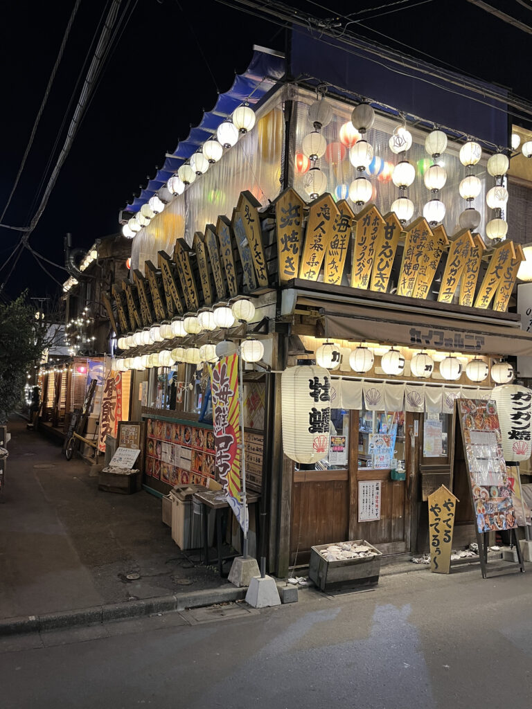 Traditional Japanese izakaya at night with hanging lanterns and colorful signs in Yoyogi.