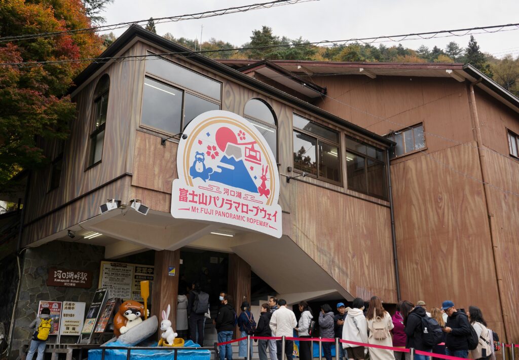 Entrance of the Mt. Fuji Panoramic Ropeway with people queuing under a sign featuring cartoon rabbits.