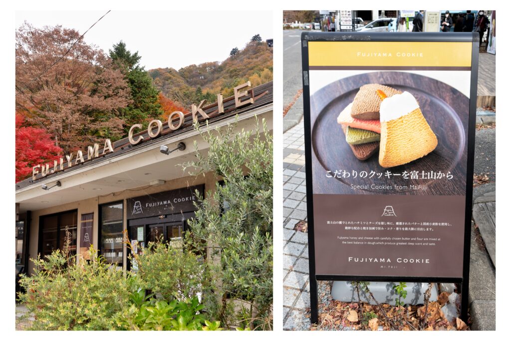 A cozy shopfront of Fujiyama Cookie surrounded by lush autumn foliage. Beside it, a signboard displays colorful Mt. Fuji-shaped cookies available in the store.