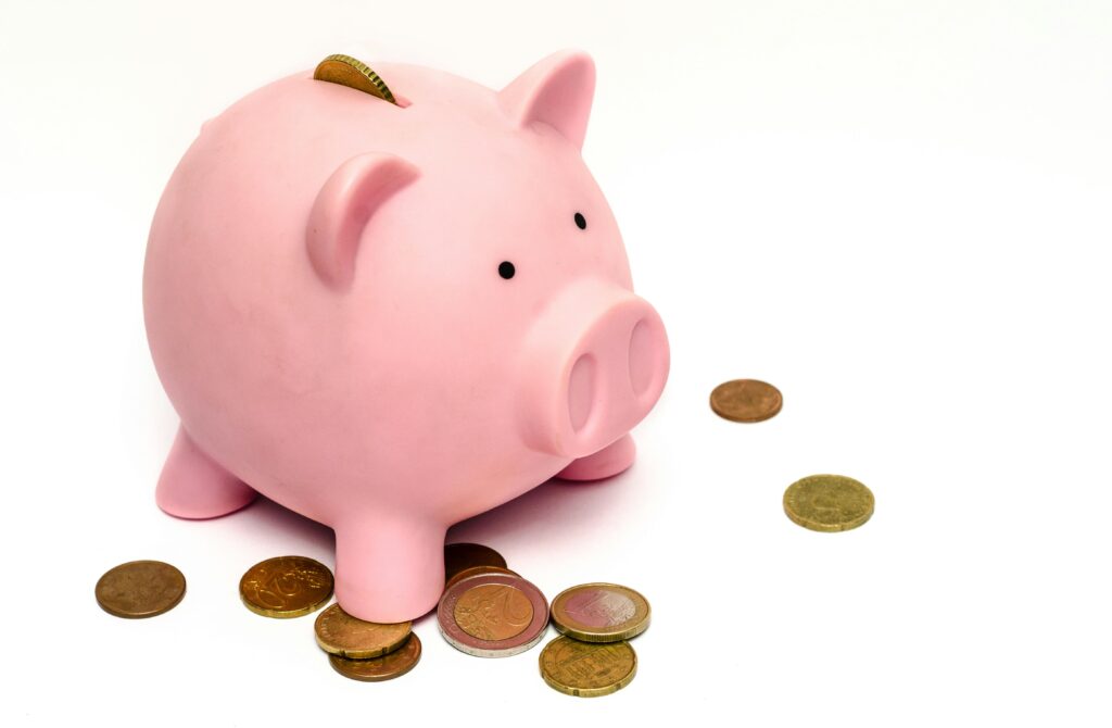 A pink piggy bank with scattered coins, representing small savings over time in Japan.