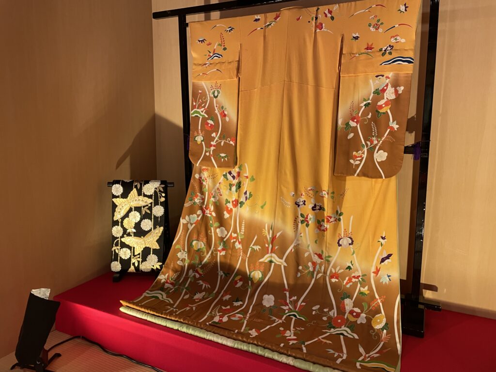 Exquisite gold kimono with intricate seasonal floral embroidery on display in Kyoto.