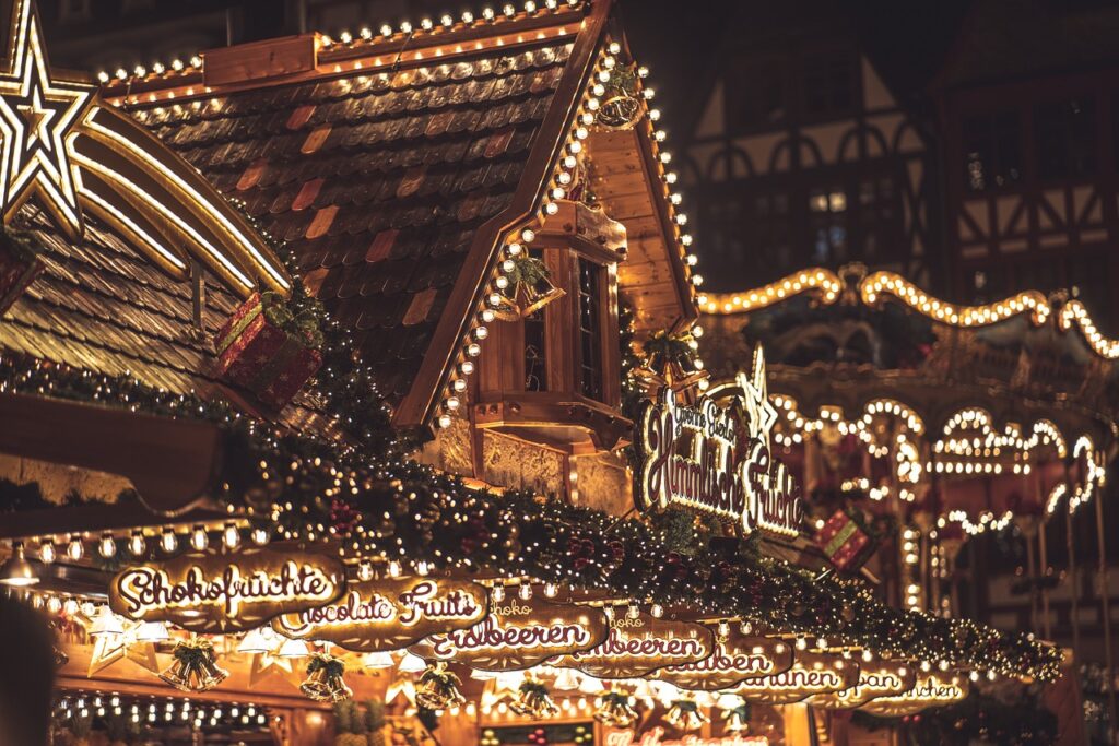  A cozy Christmas market stall glowing with lights, featuring festive garlands and signage.