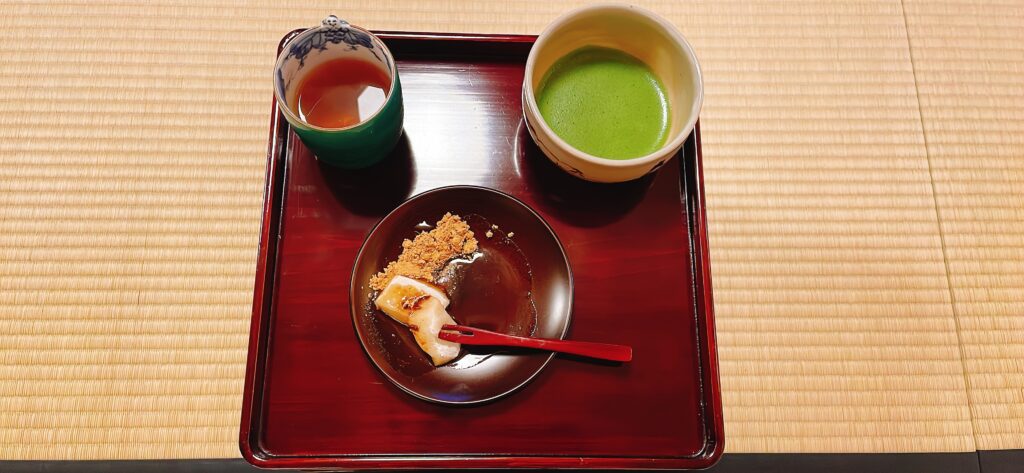 Traditional matcha tea and mochi served on a tatami mat during the geiko house experience.