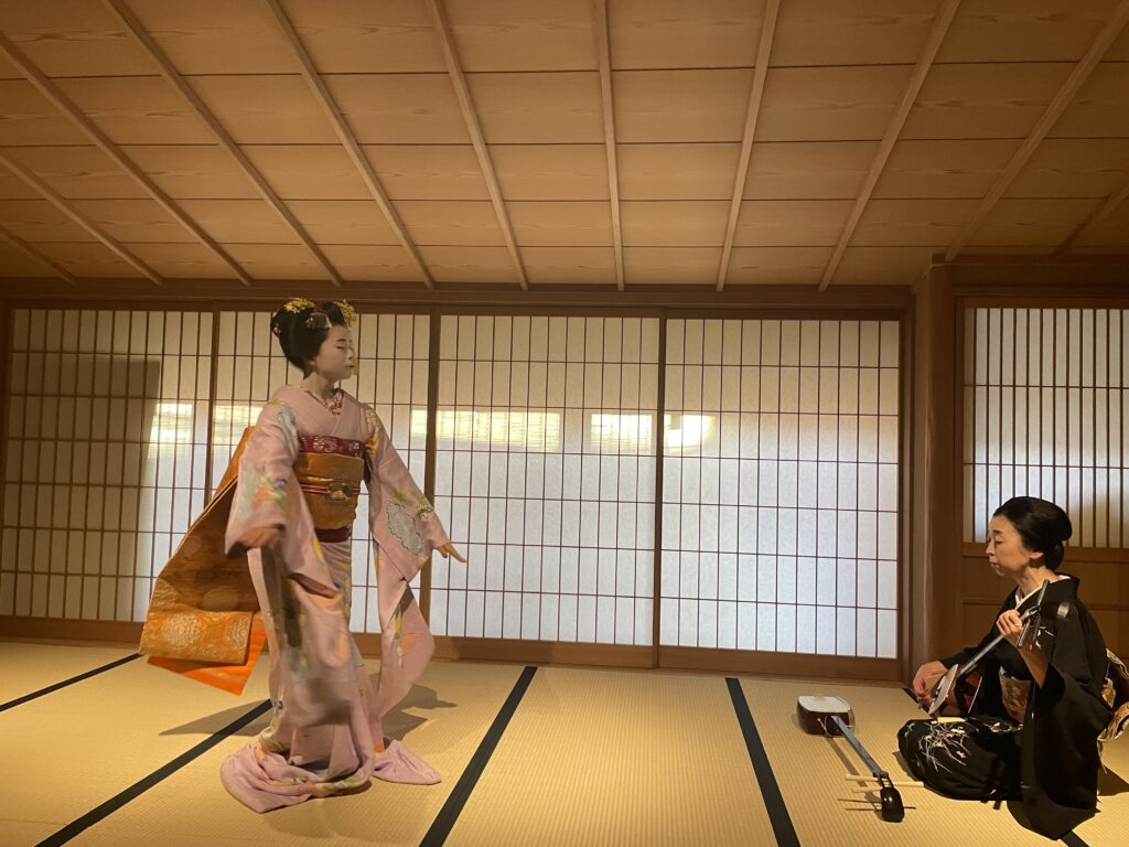 Close-up of a maiko dancing in a serene Kyoto setting.