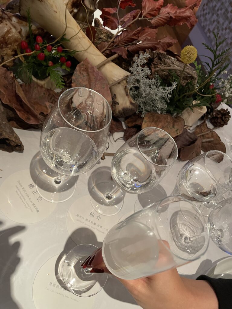 A table adorned with wine glasses and an artistic centerpiece of autumn leaves and branches.