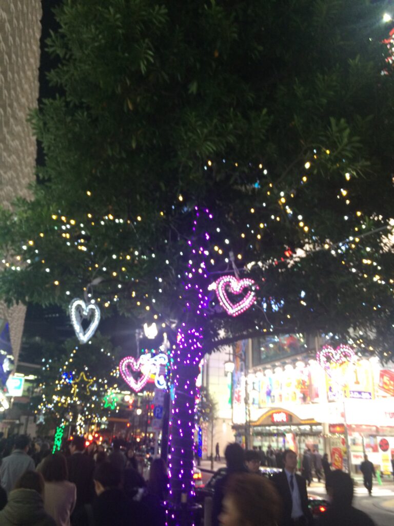 Vibrant blue Christmas illuminations featuring towering trees lit up with sparkling white and blue lights in a city square.