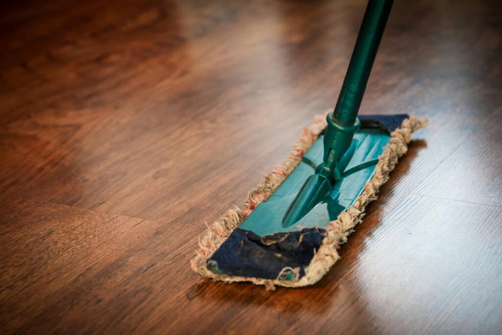 A mop cleaning a wooden floor in an empty room, ensuring the apartment is dust-free before moving in.