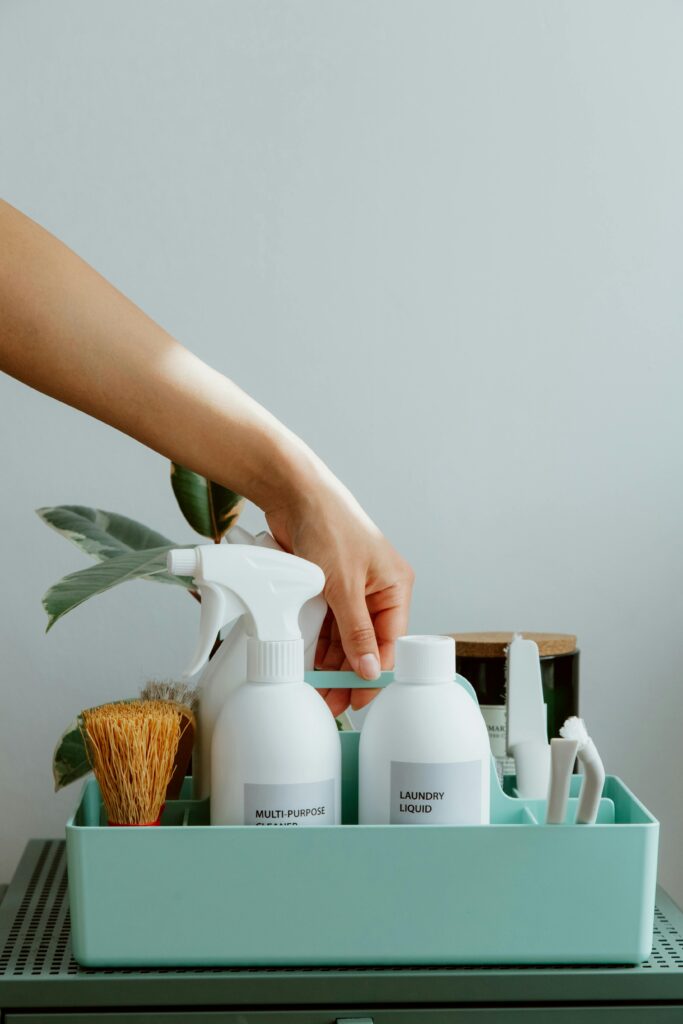 A neatly arranged caddy with cleaning supplies, including multi-purpose cleaner and laundry liquid.