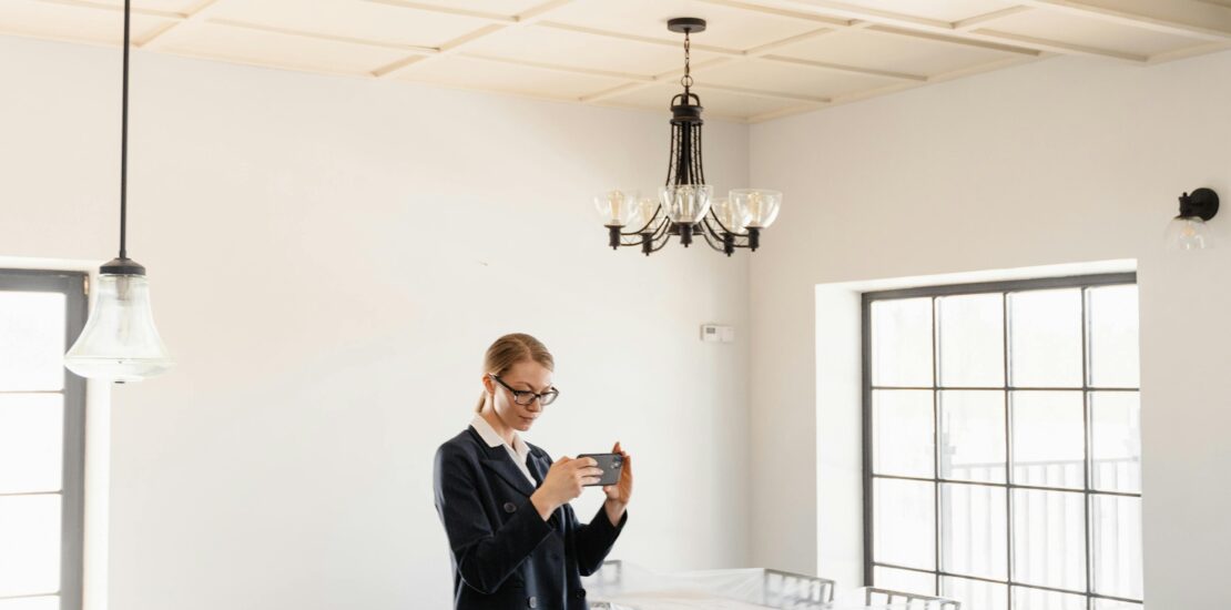 A woman in formal attire taking pictures of a newly rented apartment’s condition for documentation.