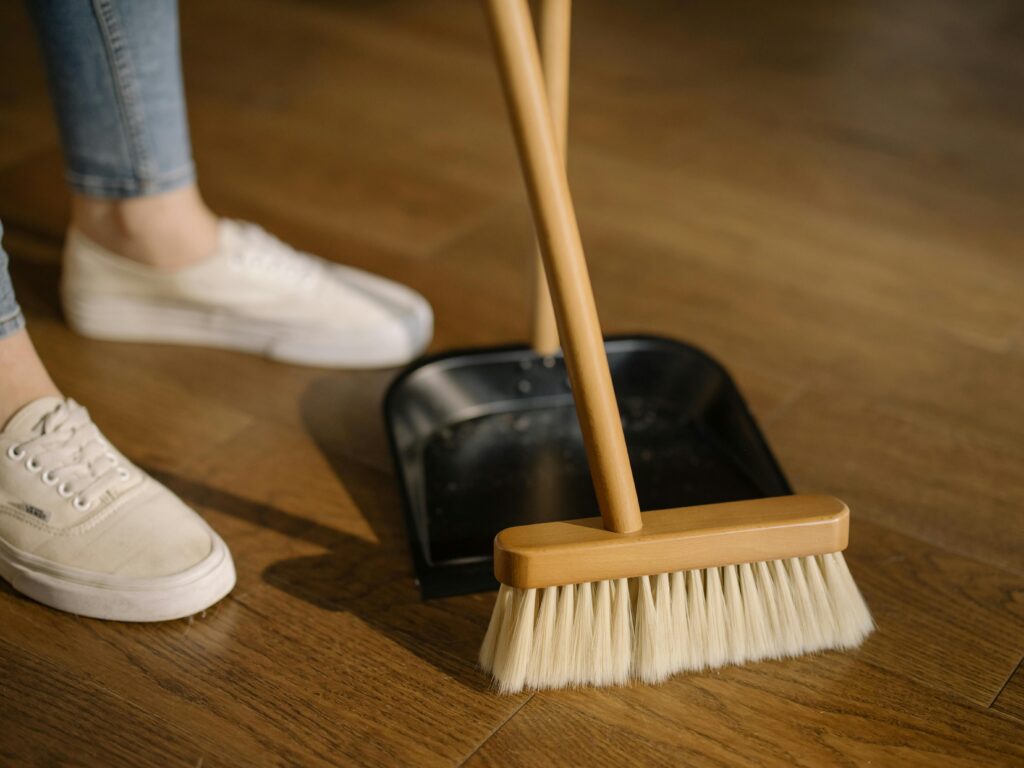 A person cleaning the floor with a broom and dustpan.