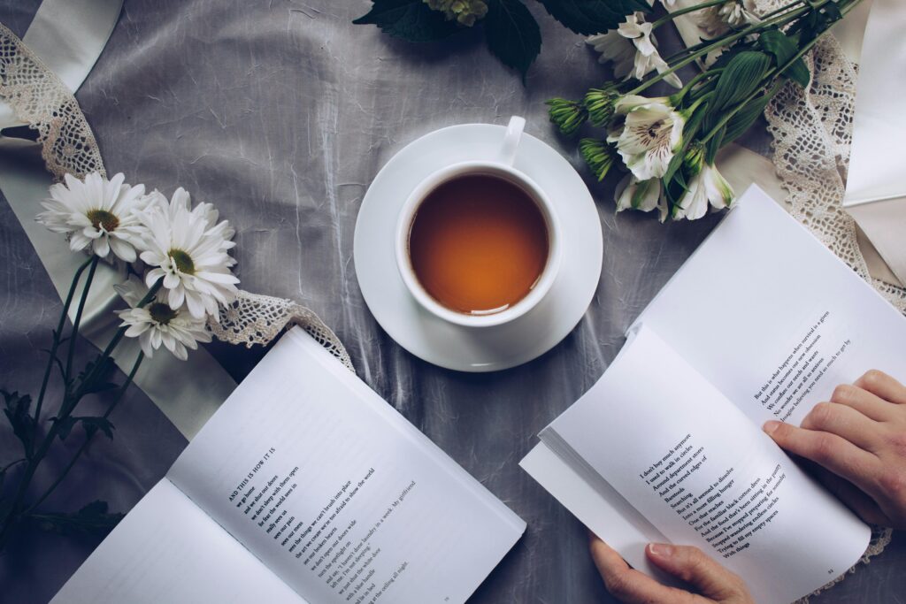 A cup of coffee, a watch, and an open planner on a wooden desk.