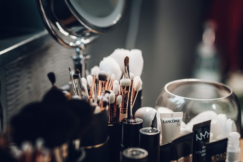  A collection of professional makeup brushes and beauty products on a dressing table, with a mirror in the background.