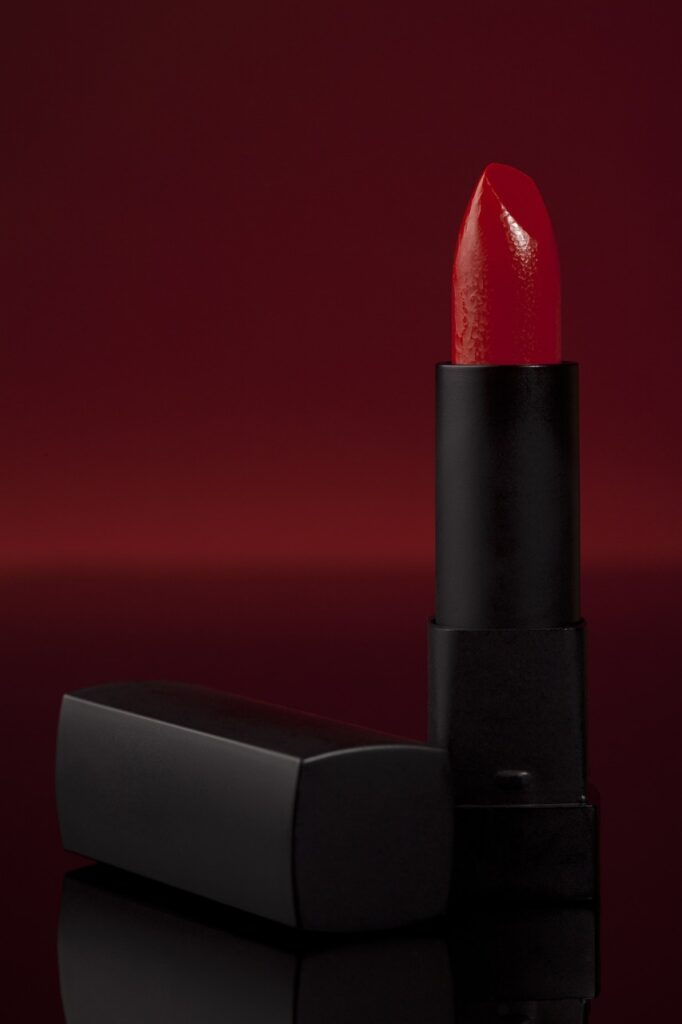 A vibrant red lipstick against a rich burgundy background, showcasing bold beauty trends in Japan.