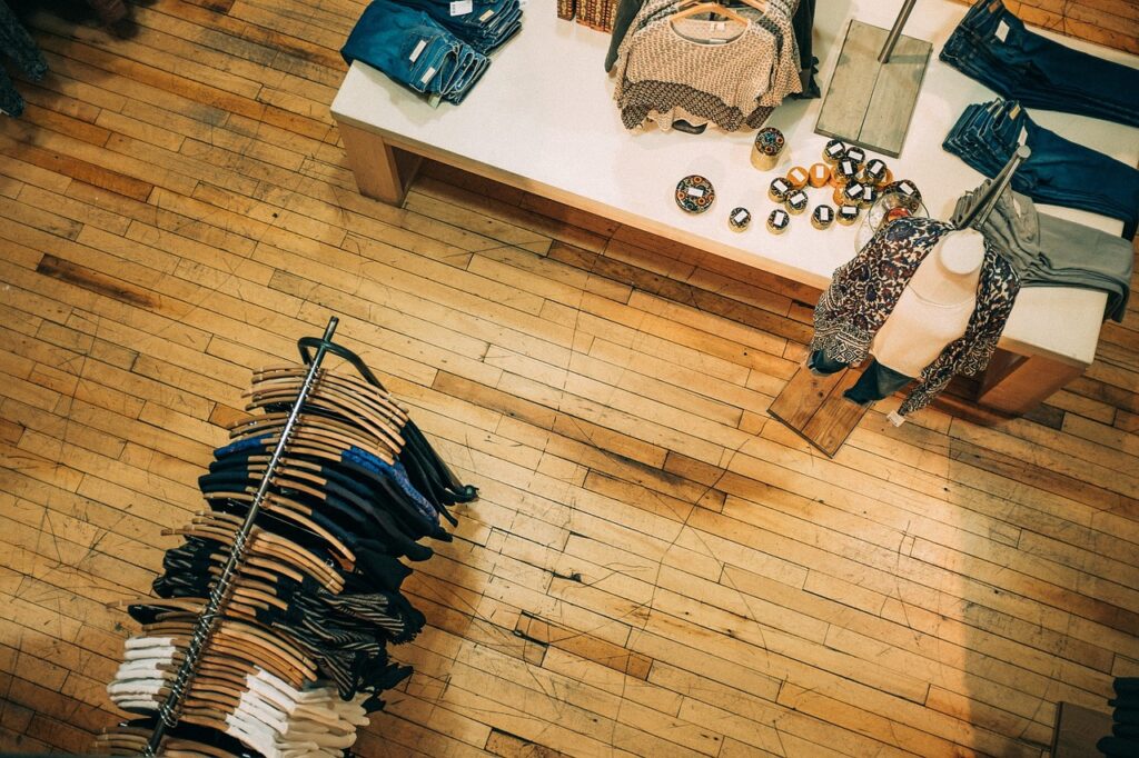 An overhead view of a wooden-floored store displaying racks of formal dress and a table adorned with small items.