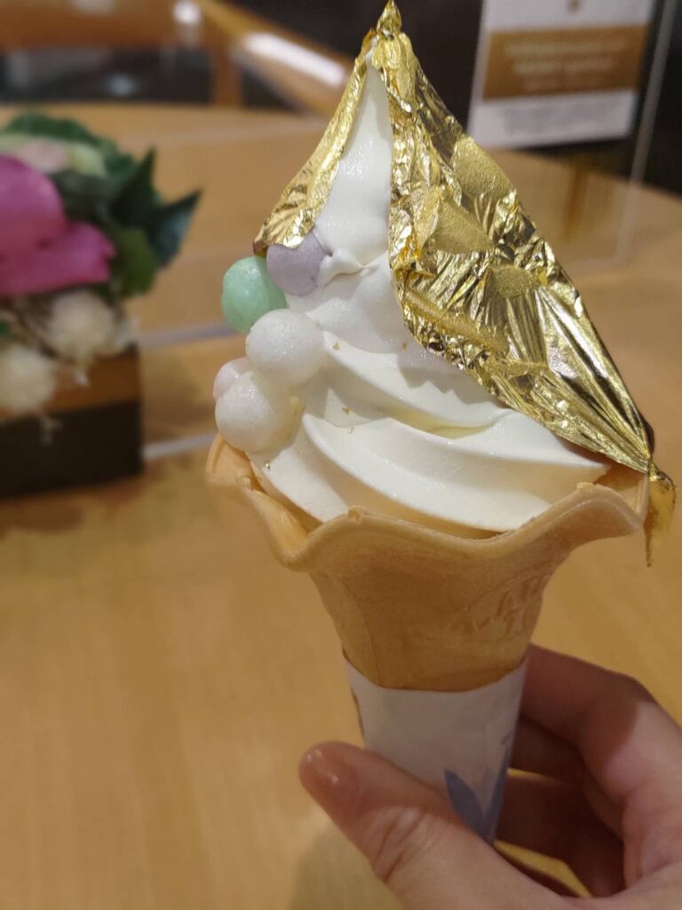 A gold leaf-covered ice cream cone held in hand, showcasing the luxurious treat famous in Kanazawa.