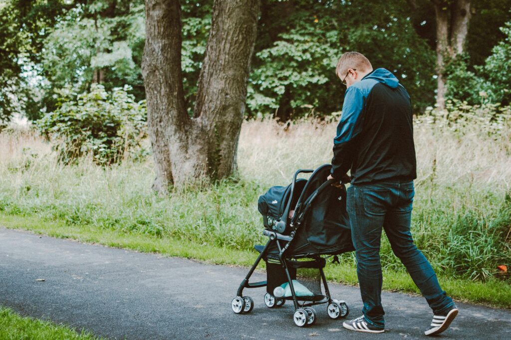 A father pushing a baby stroller through a park, highlighting how Japan is stroller-friendly with accessible pathways and green spaces.