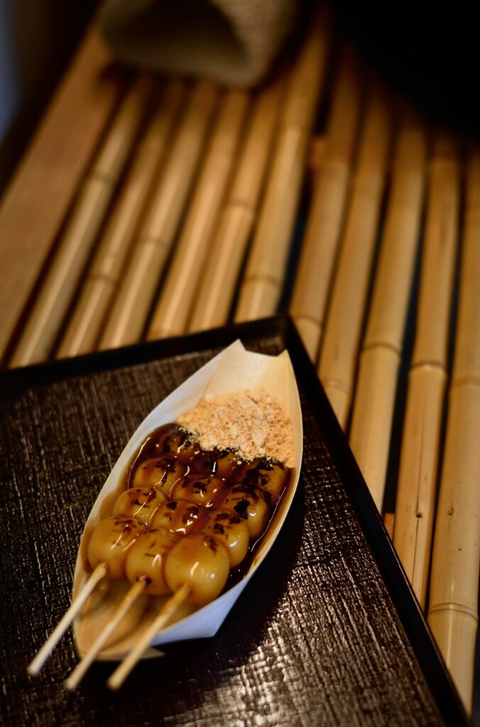 Three skewers of freshly grilled dango drizzled with a sweet soy glaze, served with kinako powder on the side in convenience stores