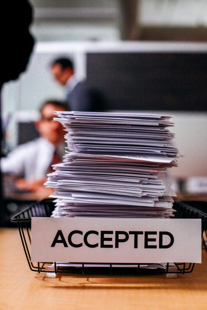 A large stack of documents in an office tray labeled "Accepted."